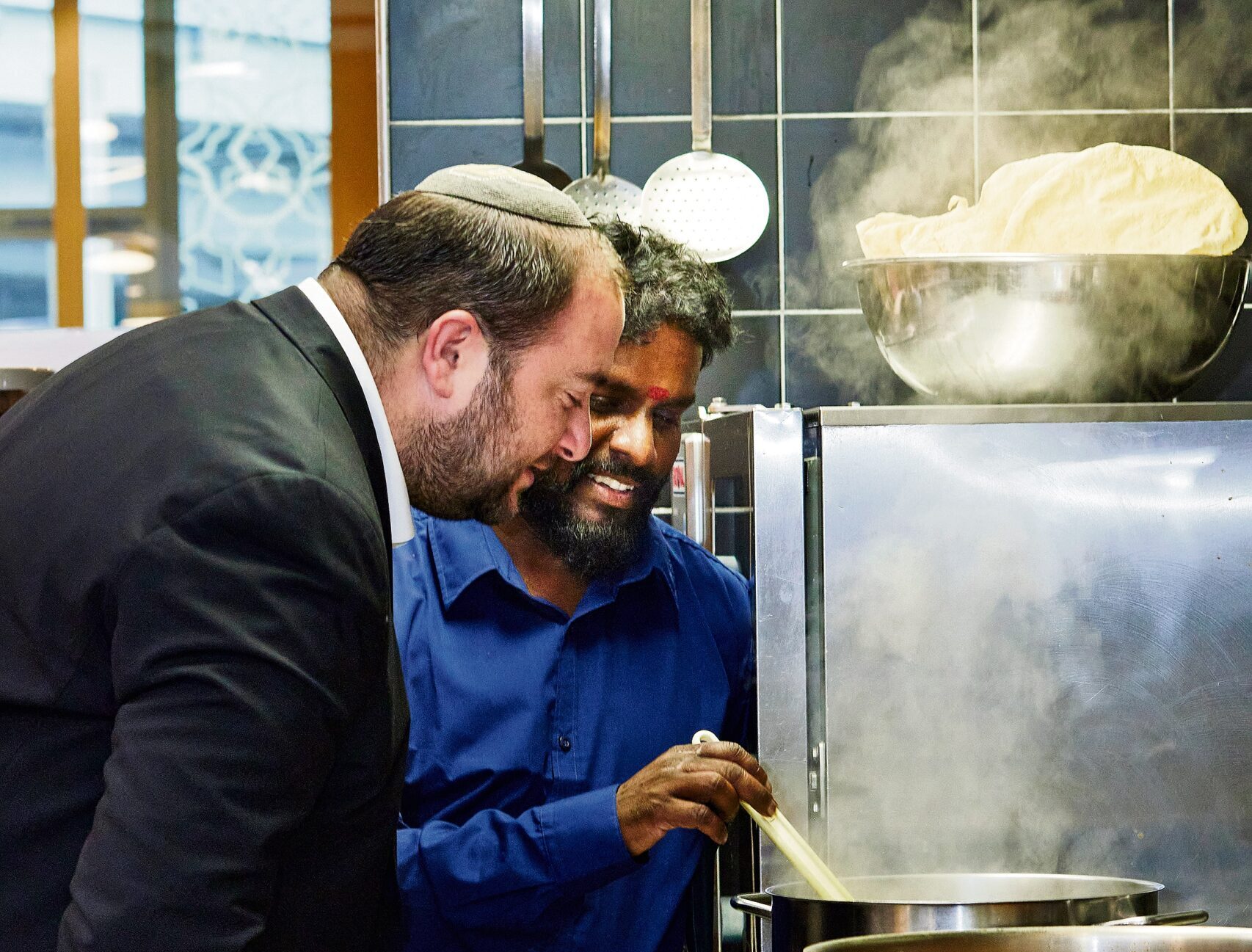 Religion geht durch den Magen: Michael Kohn und Sasikumar Tharmalingam in der Küche des Hauses der Religionen in Bern. Foto: Annette Boutellier